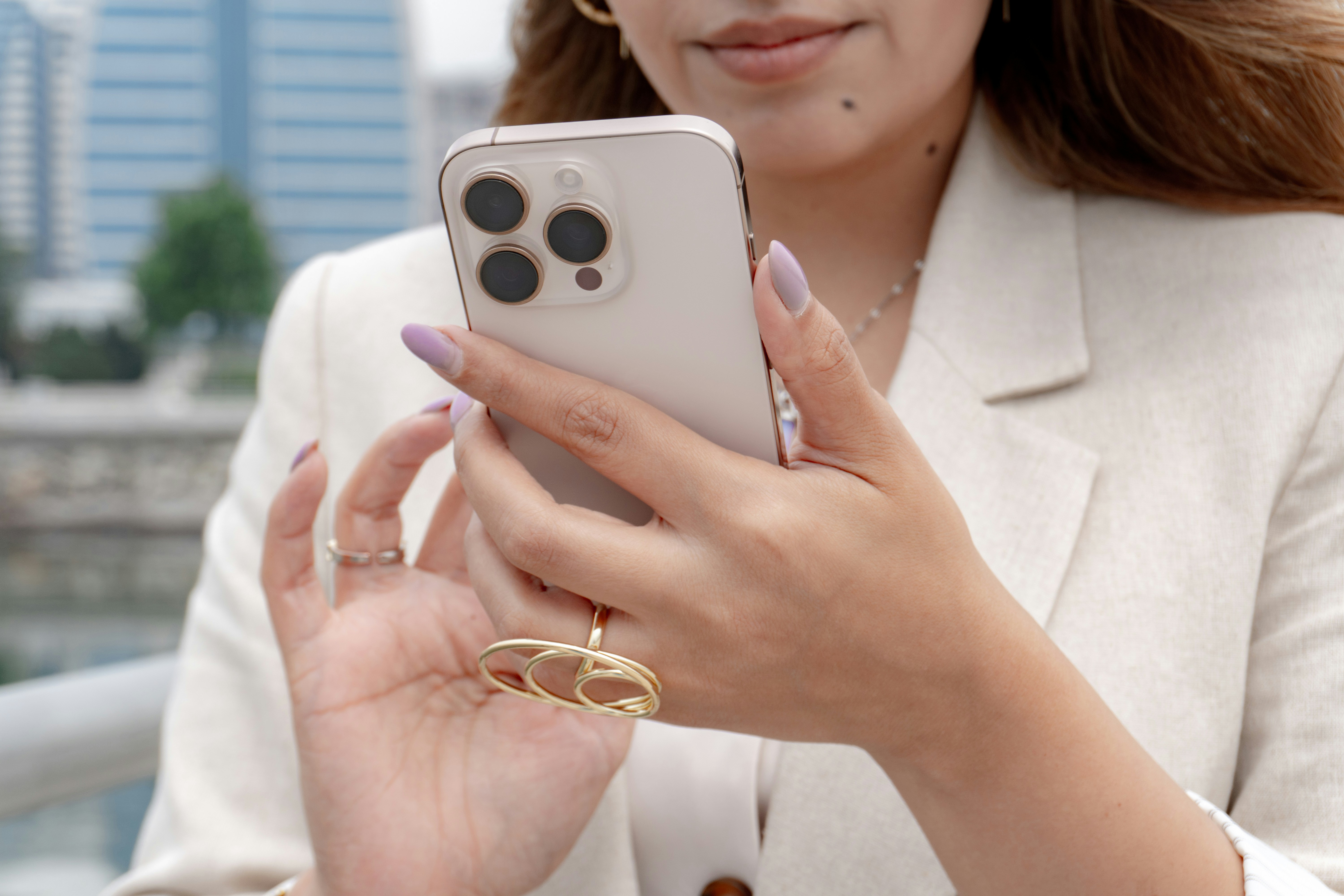 Woman holding an iPhone with city buildings blurred in the background